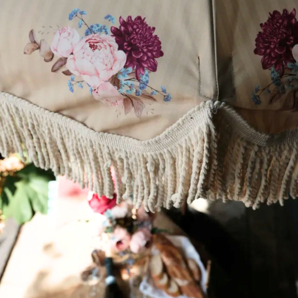 Vintage-inspired fringed garden parasol with decorative tassel fringe and beechwood pole with vintage floral motif