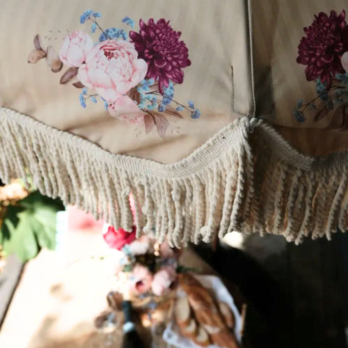 Vintage-inspired fringed garden parasol with decorative tassel fringe and beechwood pole with vintage floral motif