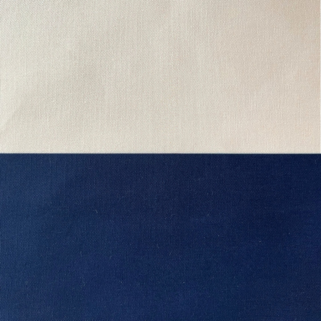 A close-up of a fabric or material swatch split horizontally into two color blocks: a warm off-white/cream section on top and a deep navy blue section on the bottom.