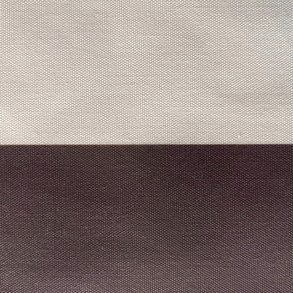 A close-up of a woven fabric texture split horizontally into two solid sections: a light warm gray/beige on top and a dark charcoal gray on the bottom.